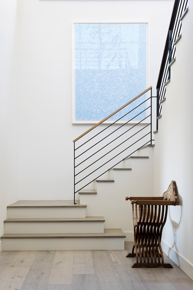 Foto de escalera en U campestre con escalones de madera, contrahuellas de madera pintada y barandilla de metal
