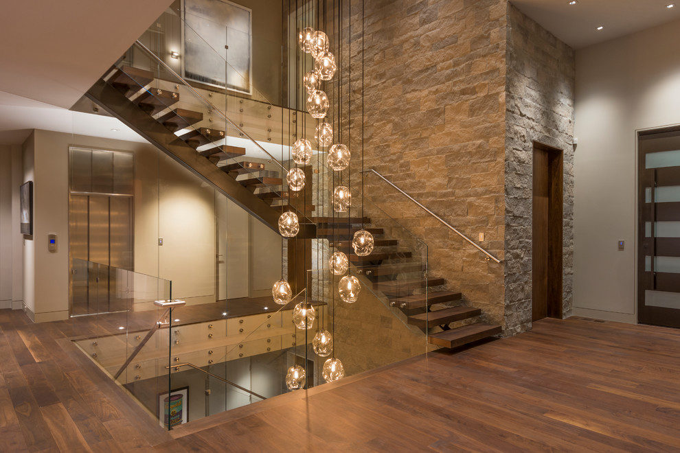 Ejemplo de escalera en L contemporánea sin contrahuella con escalones de madera y barandilla de vidrio
