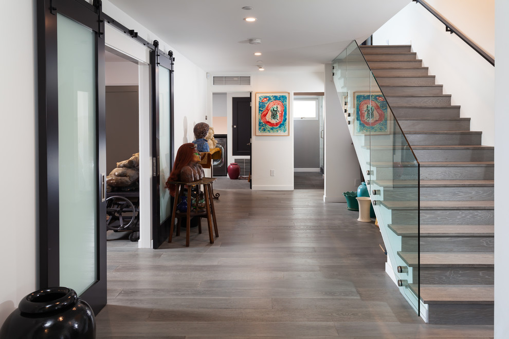 Cette image montre un escalier droit design de taille moyenne avec des marches en bois, des contremarches en bois et un garde-corps en verre.