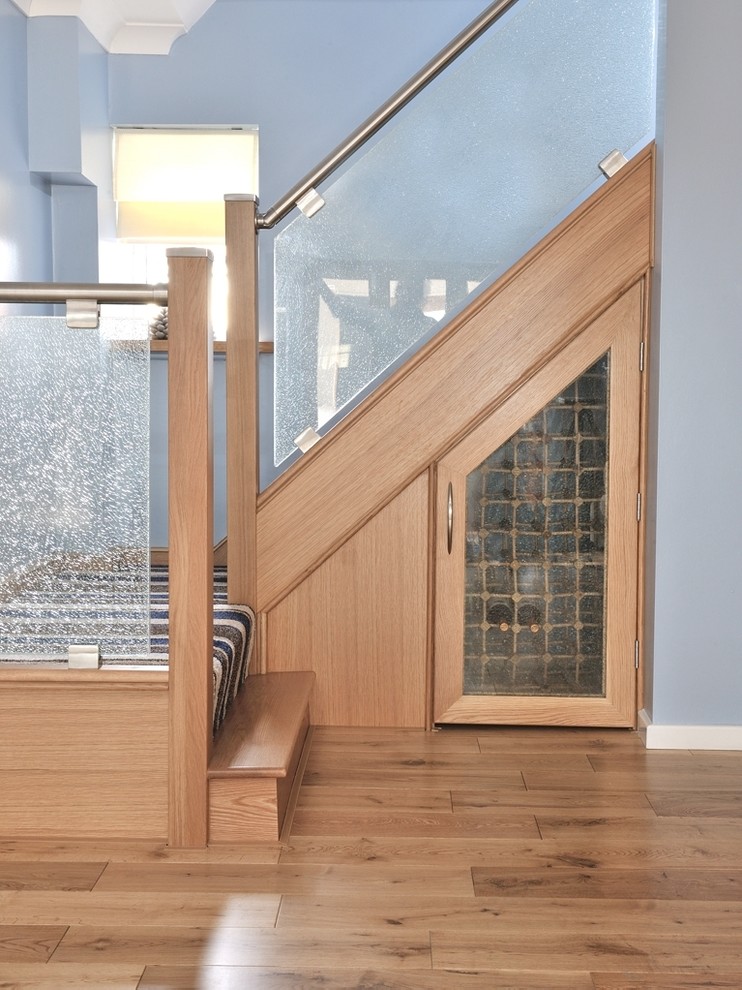Modern inredning av en mellanstor svängd trappa i glas, med sättsteg i trä och räcke i metall