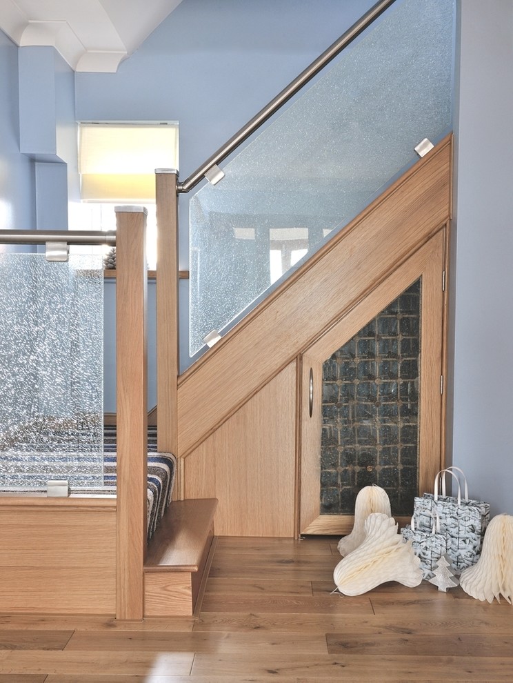 Aménagement d'un escalier courbe contemporain de taille moyenne avec des marches en verre, des contremarches en bois et un garde-corps en métal.