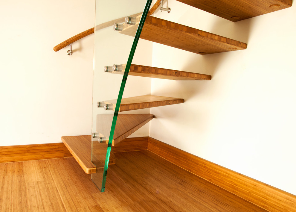 Réalisation d'un petit escalier courbe design avec des marches en bois, des contremarches en bois et un garde-corps en matériaux mixtes.