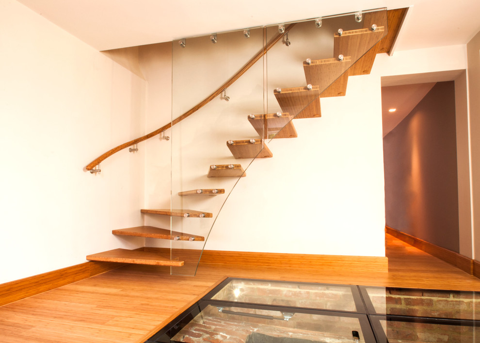 Idée de décoration pour un petit escalier courbe design avec des marches en bois, des contremarches en bois et un garde-corps en matériaux mixtes.