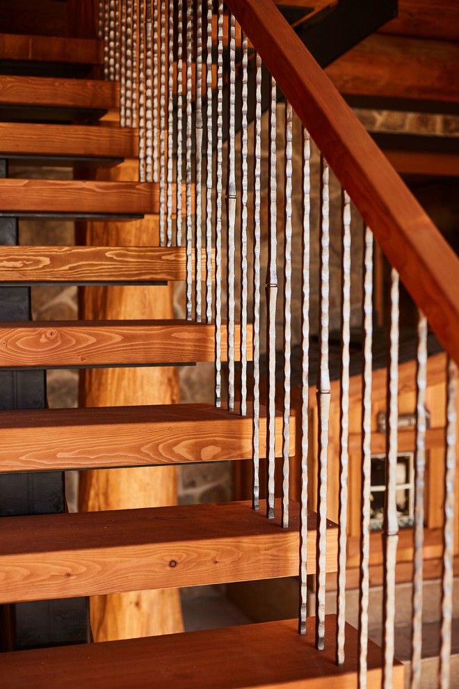 Rustik inredning av en flytande trappa i trä, med öppna sättsteg och räcke i flera material