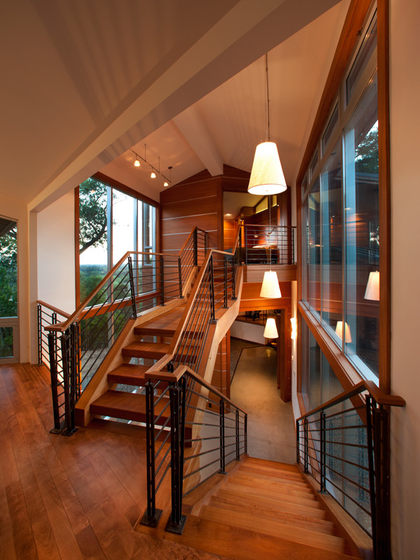 Стильный дизайн: большая лестница на больцах в современном стиле с деревянными ступенями и перилами из смешанных материалов без подступенок - последний тренд