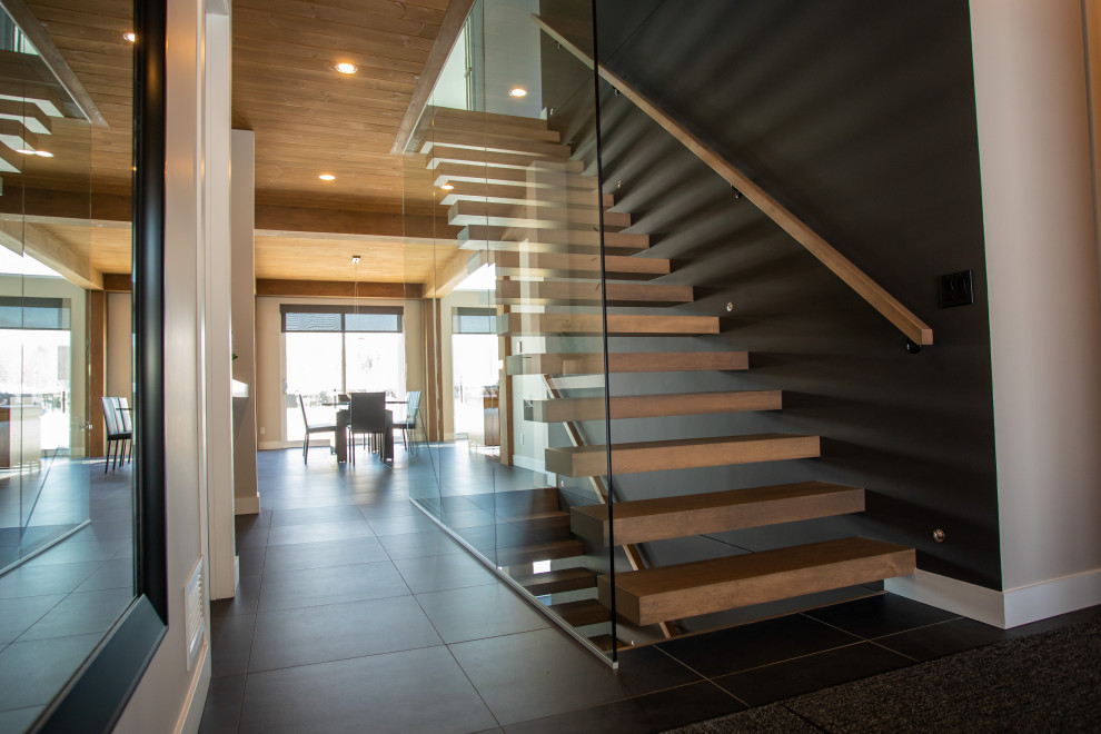 На фото: прямая лестница в стиле модернизм с деревянными ступенями и стеклянными перилами без подступенок