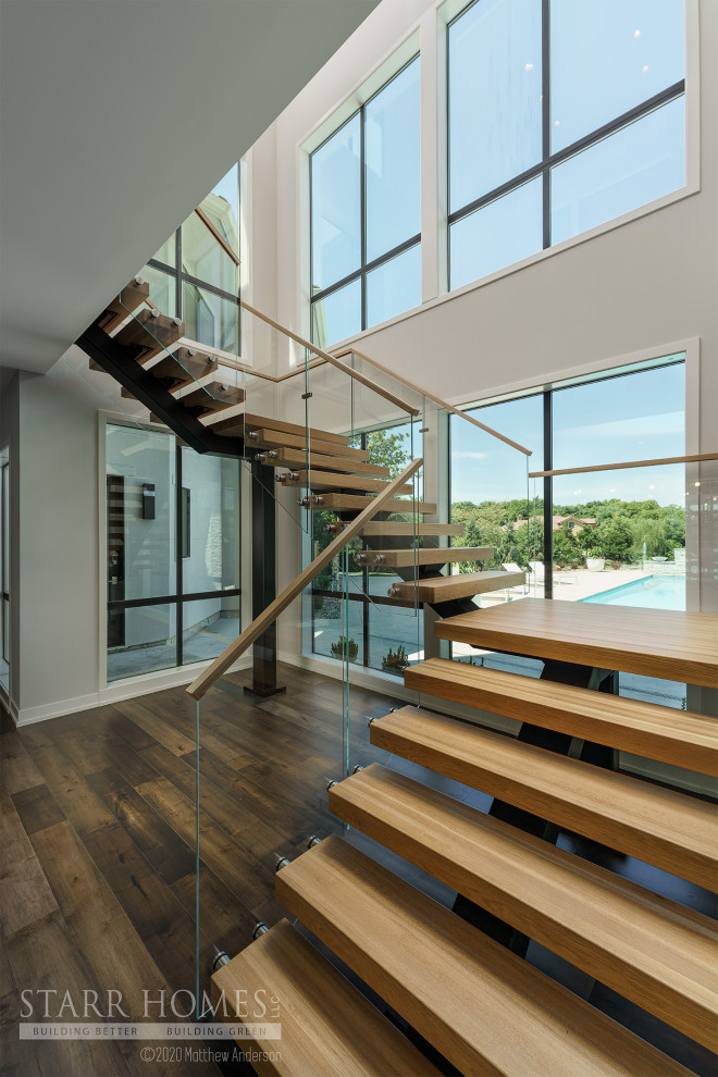 Ejemplo de escalera minimalista sin contrahuella con barandilla de vidrio y madera