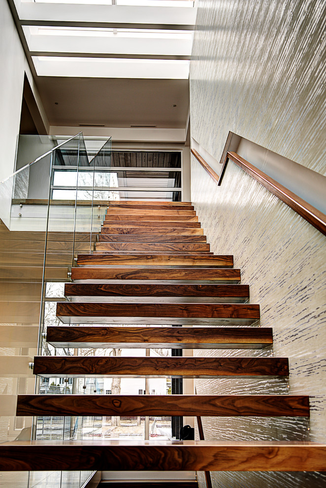 Стильный дизайн: лестница на больцах в современном стиле с деревянными ступенями и стеклянными перилами без подступенок - последний тренд