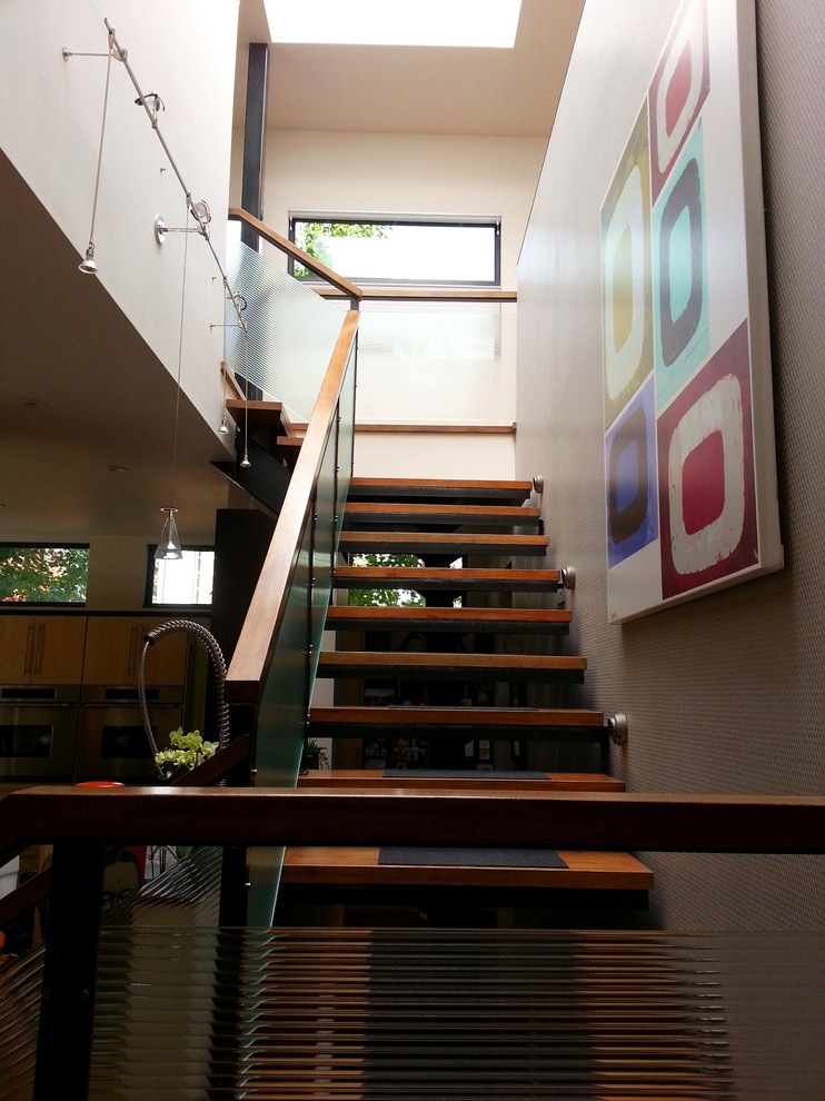This is an example of an expansive retro wood floating staircase in Denver with metal risers and feature lighting.