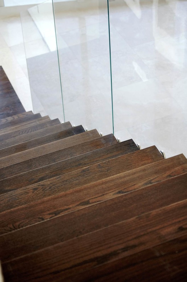 タンパにある中くらいなコンテンポラリースタイルのおしゃれな直階段 (木の蹴込み板、ガラスフェンス) の写真