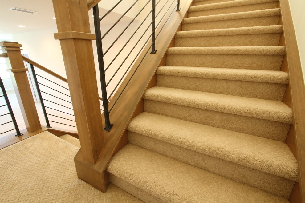Cette photo montre un grand escalier chic en U avec des marches en moquette, des contremarches en moquette et un garde-corps en bois.
