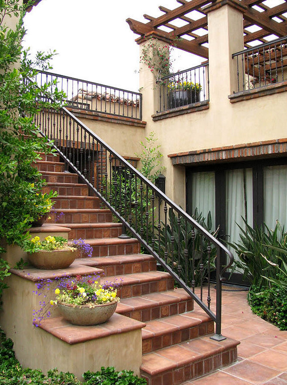 Ejemplo de escalera recta de tamaño medio con escalones de terracota, contrahuellas de terracota y barandilla de metal