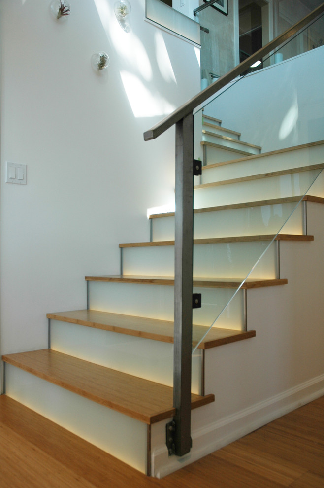 На фото: угловая лестница среднего размера в современном стиле с деревянными ступенями и стеклянными подступенками
