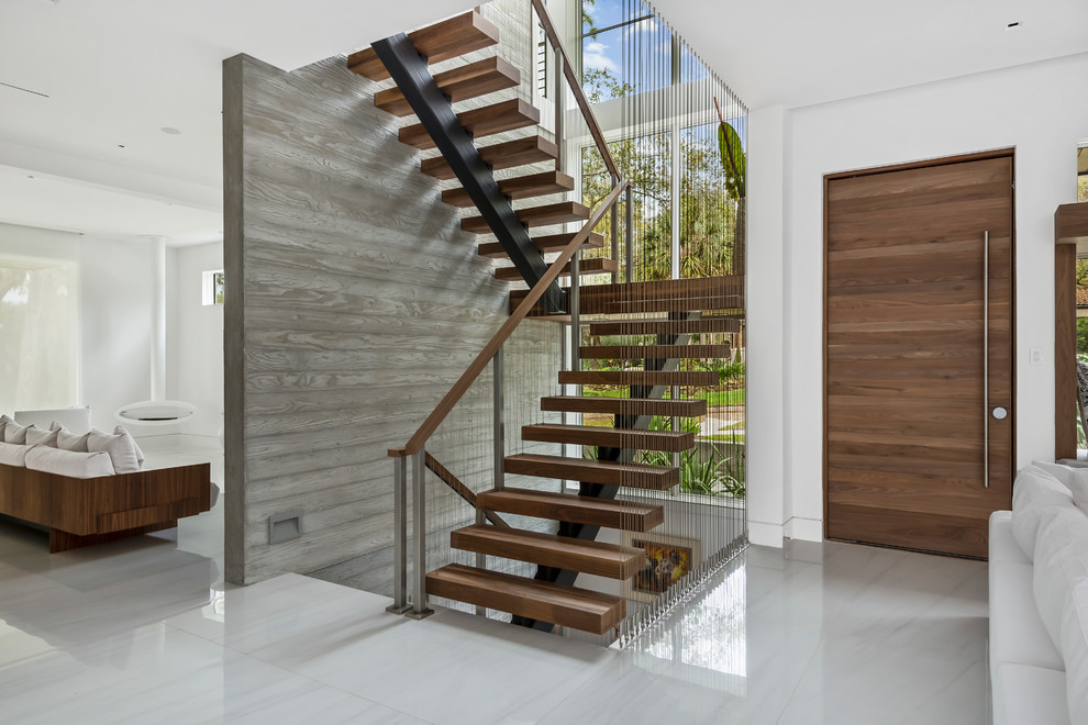 Idée de décoration pour un escalier sans contremarche flottant design avec des marches en bois, un garde-corps en câble et palier.