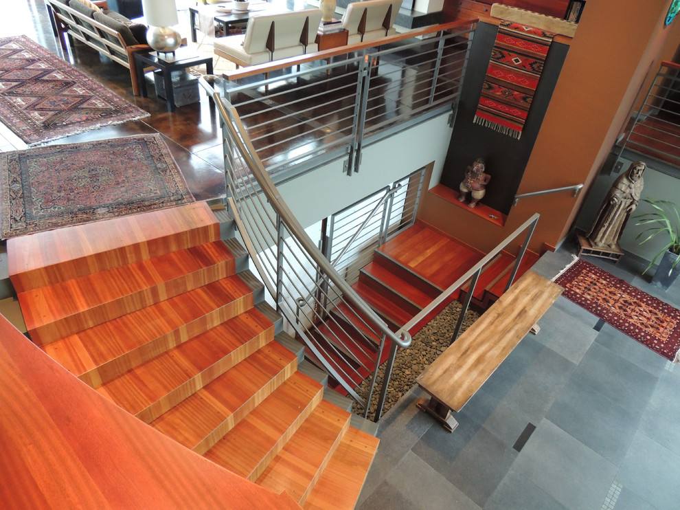 Example of a large minimalist wooden curved metal railing staircase design in Portland with wooden risers