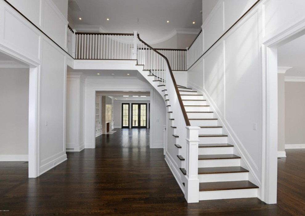 Идея дизайна: изогнутая деревянная лестница в классическом стиле с деревянными ступенями и деревянными перилами