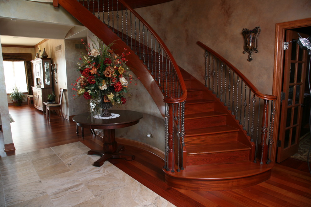 Foto de escalera curva tradicional de tamaño medio con escalones de madera, contrahuellas de madera y barandilla de metal