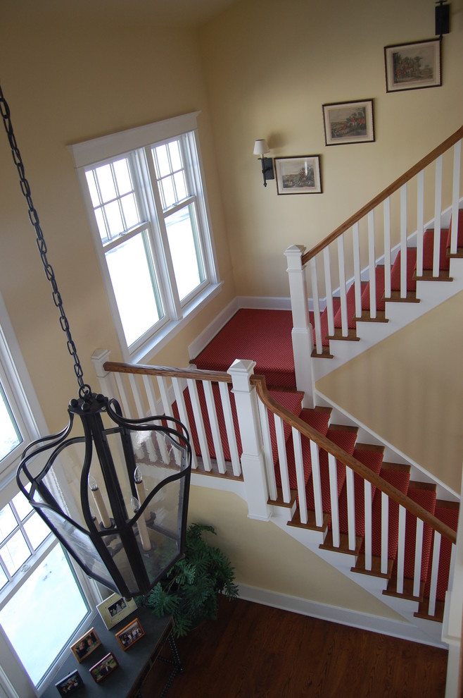 This is an example of an expansive classic wood u-shaped staircase in Bridgeport with painted wood risers.