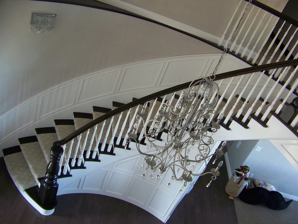 Large elegant wooden curved staircase photo in Other with painted risers