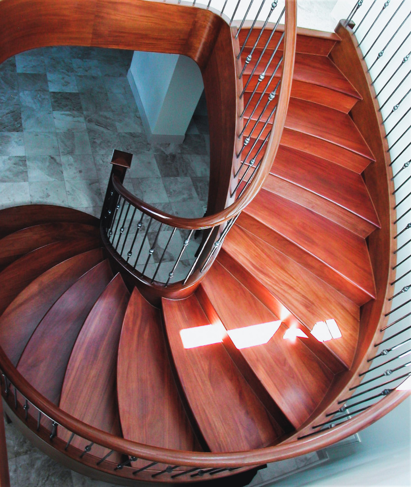 Ejemplo de escalera de caracol clásica de tamaño medio con escalones de madera, contrahuellas de madera y barandilla de metal
