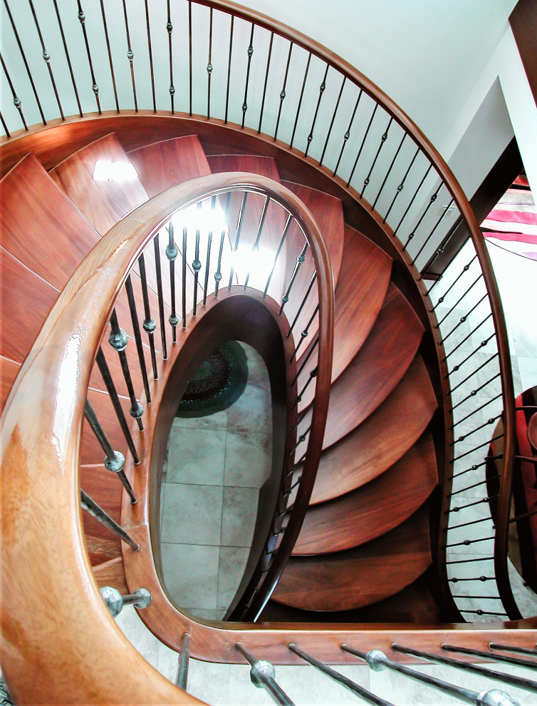 Ejemplo de escalera de caracol tradicional de tamaño medio con escalones de madera, contrahuellas de madera y barandilla de metal