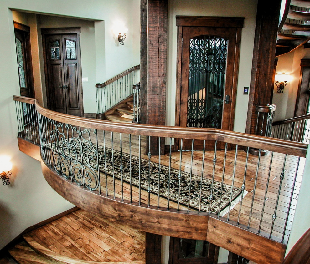 Свежая идея для дизайна: большая изогнутая лестница в классическом стиле с деревянными ступенями и металлическими перилами без подступенок - отличное фото интерьера