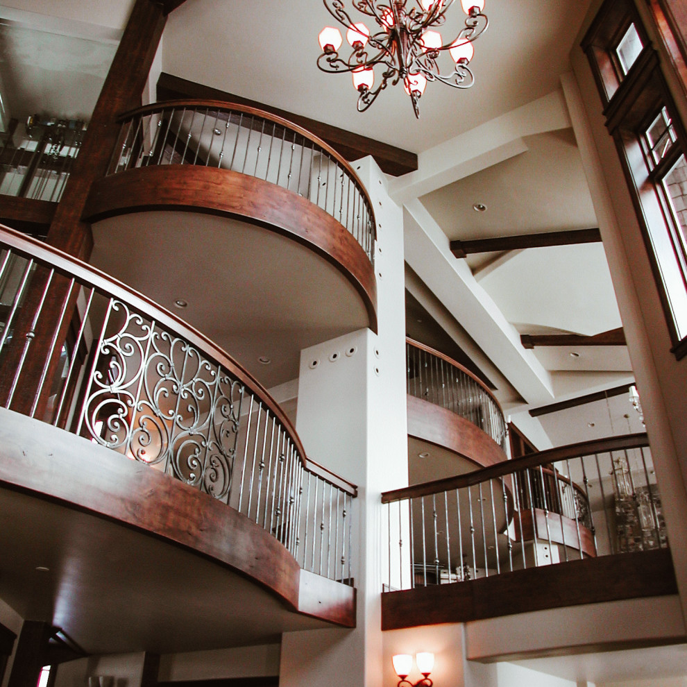 Источник вдохновения для домашнего уюта: большая изогнутая лестница в классическом стиле с деревянными ступенями и металлическими перилами без подступенок