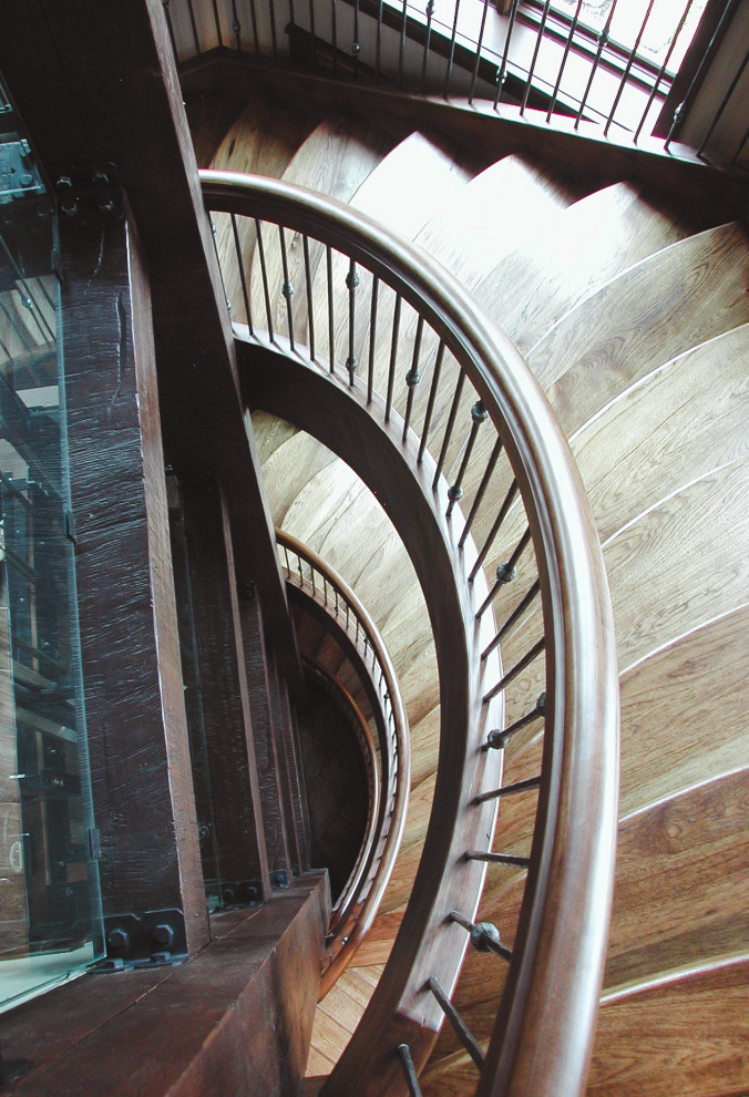 Design ideas for a large traditional wood curved metal railing staircase in Salt Lake City with open risers.