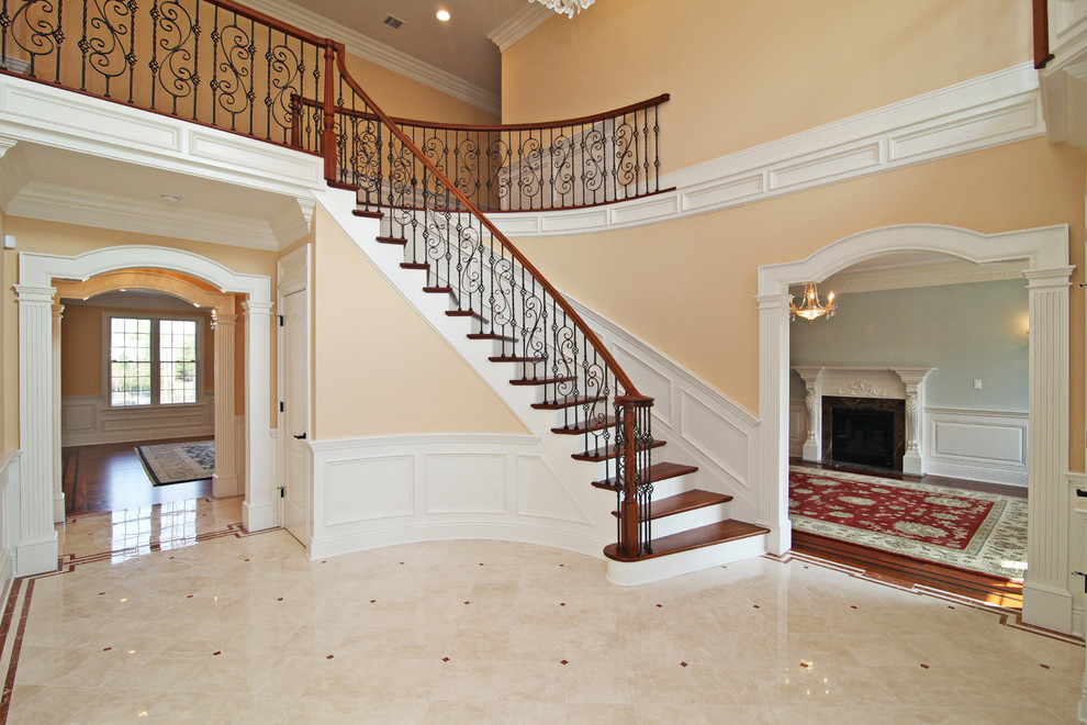 Ejemplo de escalera curva clásica grande con escalones de madera y contrahuellas de madera pintada