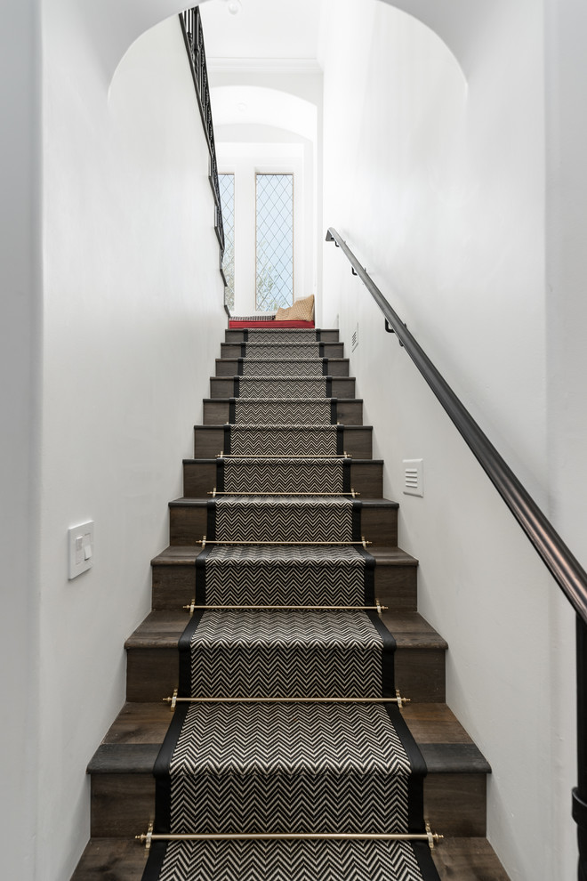 Cette photo montre un très grand escalier droit romantique avec des marches en moquette, des contremarches en bois et un garde-corps en métal.