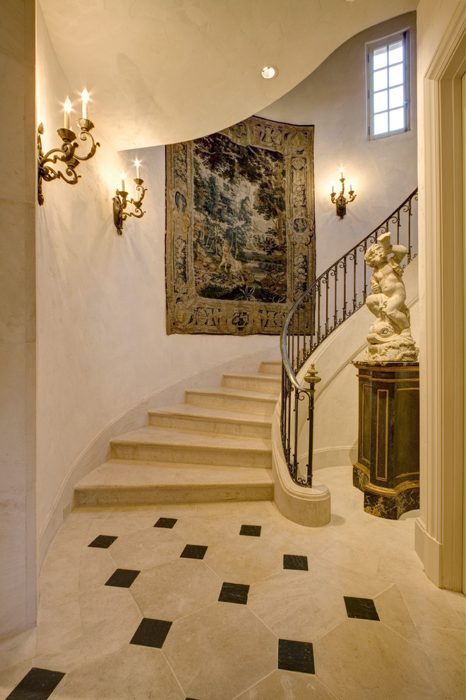 Стильный дизайн: изогнутая лестница в классическом стиле с металлическими перилами, мраморными ступенями и подступенками из мрамора - последний тренд