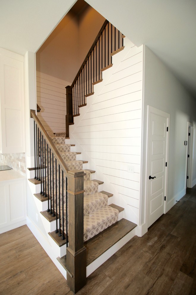 На фото: большая п-образная лестница в стиле кантри с ступенями с ковровым покрытием, ковровыми подступенками и перилами из смешанных материалов