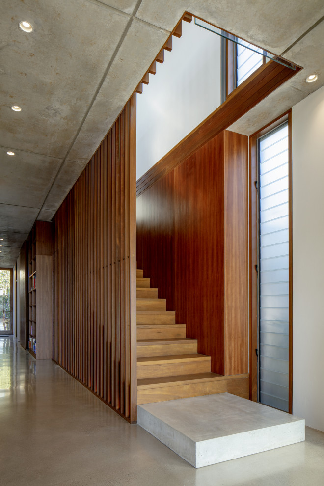Cette image montre un grand escalier droit design en bois avec des marches en bois, des contremarches en bois et un garde-corps en bois.