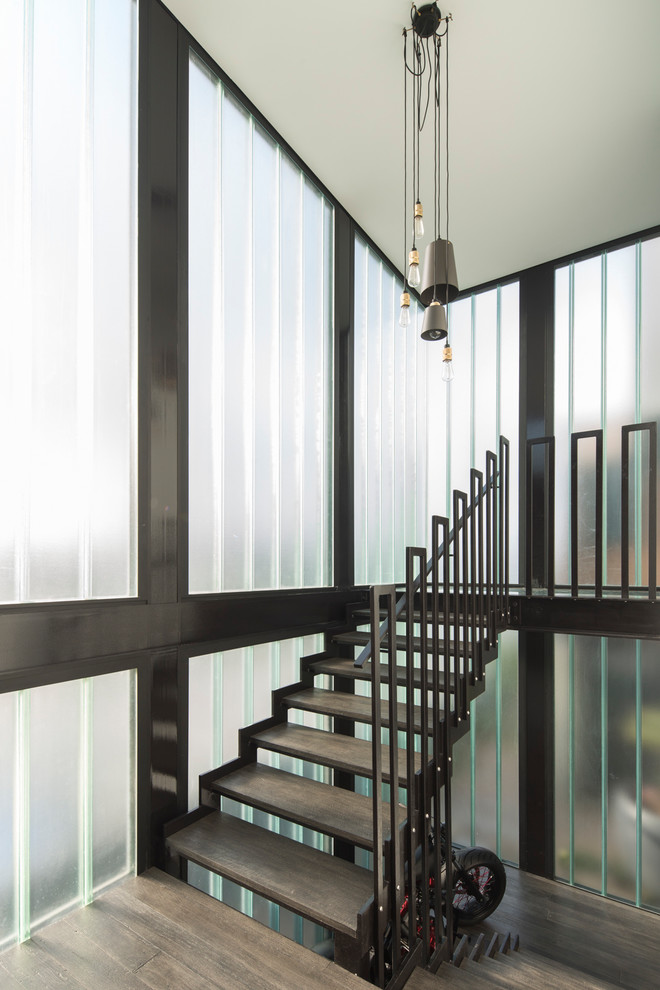 Diseño de escalera en U industrial grande sin contrahuella con escalones de madera y barandilla de metal