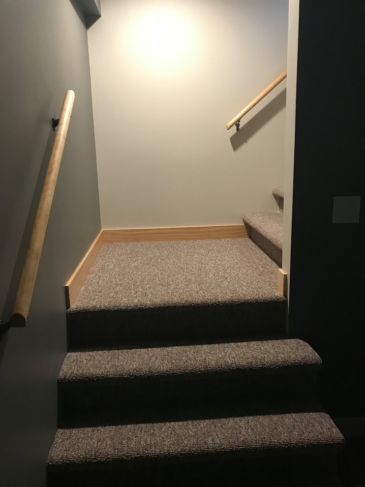 ミルウォーキーにあるラスティックスタイルのおしゃれなかね折れ階段 (カーペット張りの蹴込み板、木材の手すり) の写真