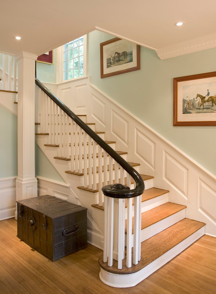 Стильный дизайн: большая угловая лестница в классическом стиле с деревянными ступенями, крашенными деревянными подступенками и деревянными перилами - последний тренд