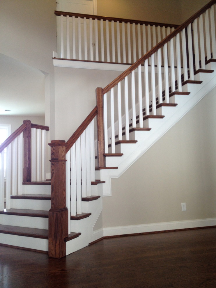 Example of an arts and crafts wooden curved staircase design in Cincinnati with painted risers