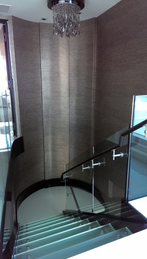 Réalisation d'un grand escalier sans contremarche minimaliste en L avec des marches en verre et un garde-corps en verre.