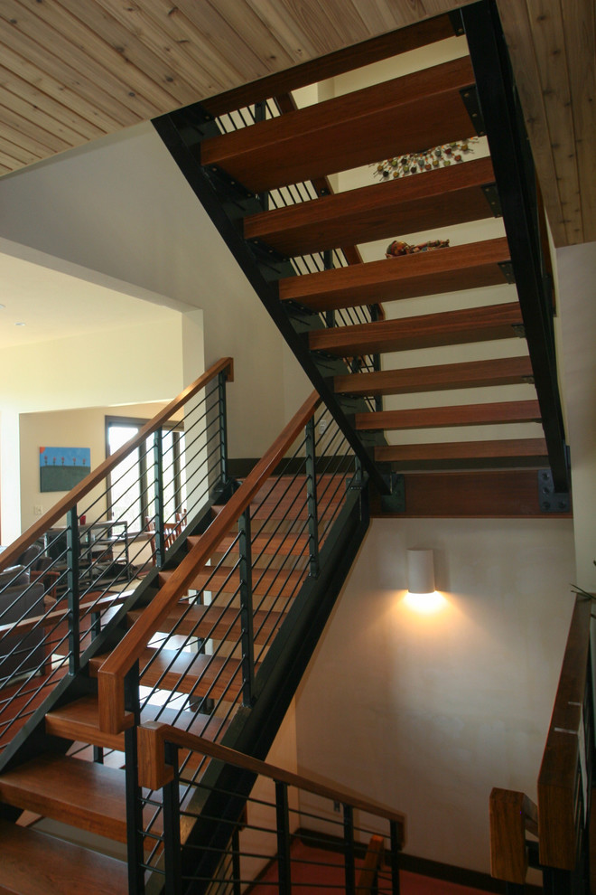 Aménagement d'un grand escalier sans contremarche moderne en U avec des marches en bois et un garde-corps en métal.