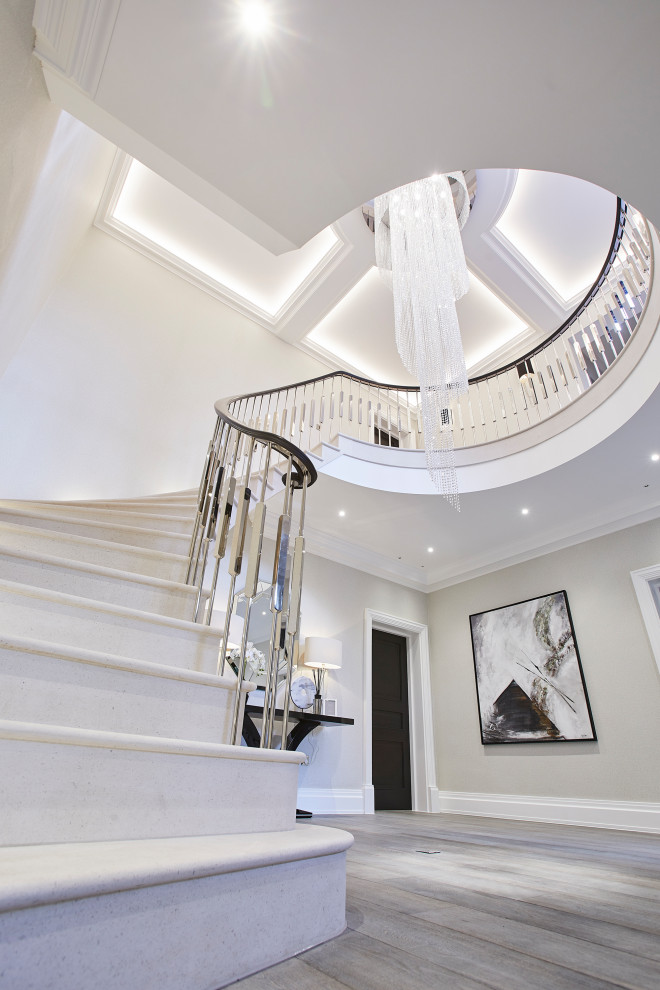 На фото: огромная изогнутая лестница в стиле модернизм с ступенями из известняка, подступенками из известняка и металлическими перилами с