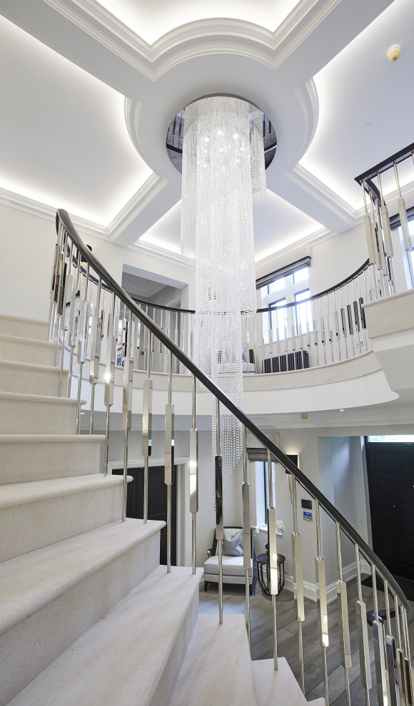 На фото: огромная изогнутая лестница в стиле модернизм с ступенями из известняка, подступенками из известняка и металлическими перилами
