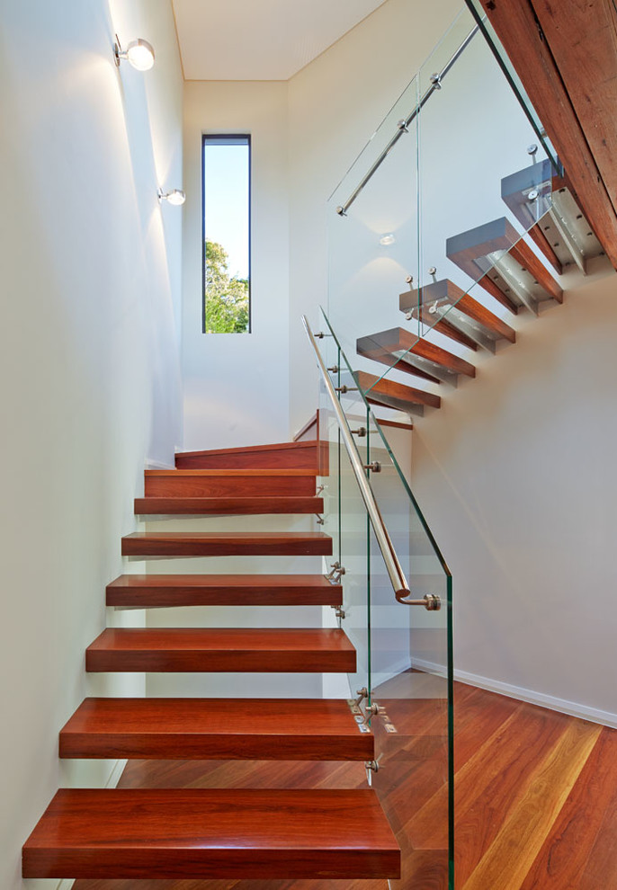 Aménagement d'un escalier sans contremarche flottant contemporain avec des marches en bois, un garde-corps en verre, palier et éclairage.