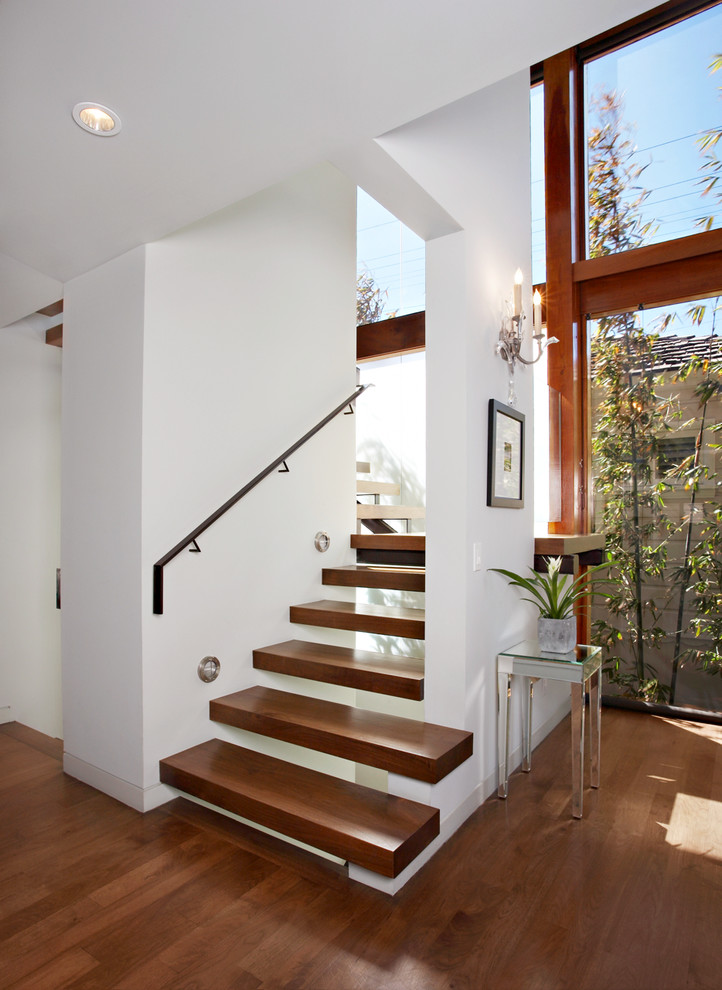 Inspiration for a contemporary wood floating staircase in Los Angeles with open risers and feature lighting.
