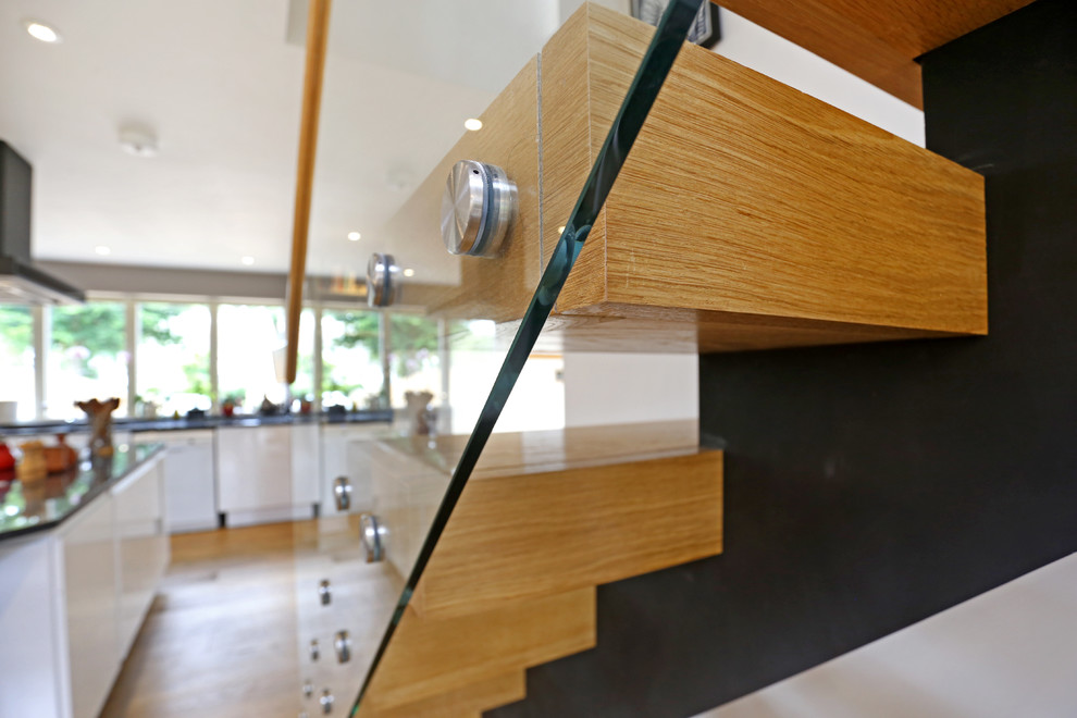 Photo of a medium sized contemporary wood straight glass railing staircase in Wiltshire with wood risers.