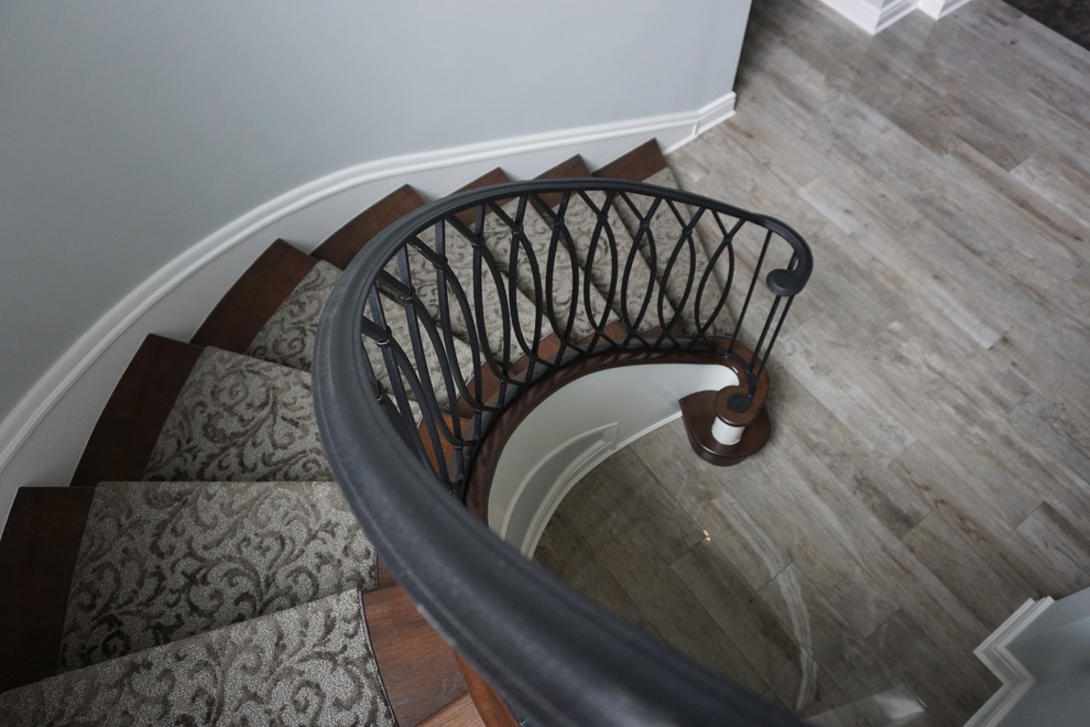 Стильный дизайн: большая винтовая металлическая лестница в стиле ретро с ступенями с ковровым покрытием - последний тренд