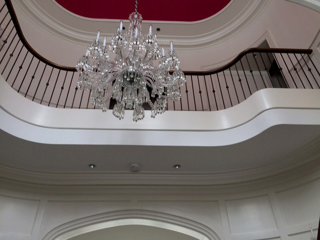 Пример оригинального дизайна: большая изогнутая лестница в классическом стиле с деревянными ступенями и крашенными деревянными подступенками