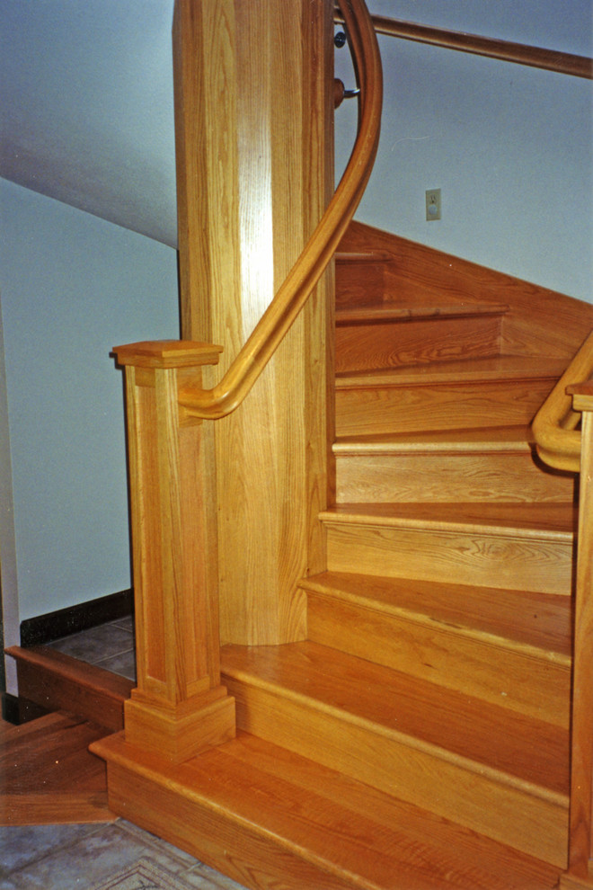 Foto di una grande scala a chiocciola american style con pedata in legno e alzata in legno