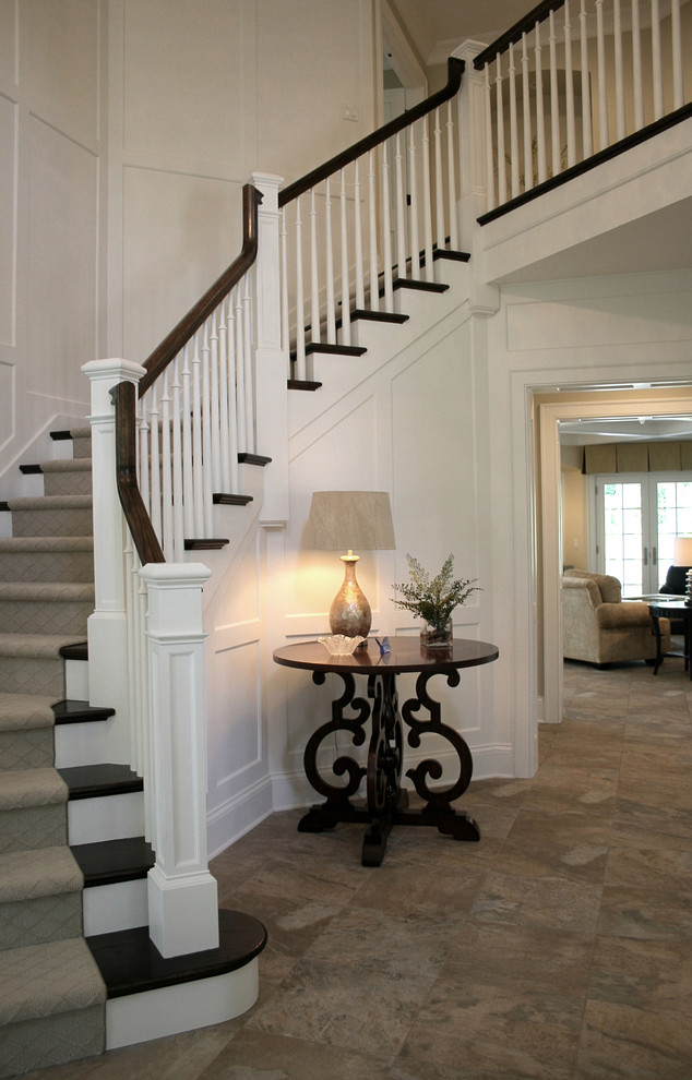 Foto de escalera curva clásica grande con escalones de madera, contrahuellas de madera pintada y barandilla de madera