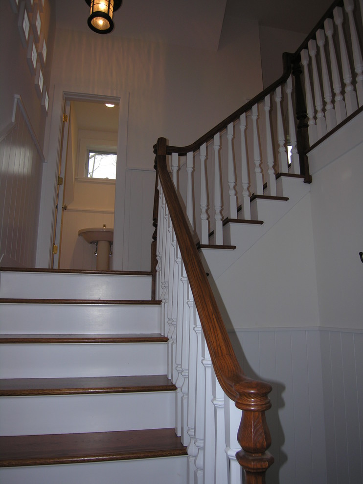 Cette image montre un grand escalier peint traditionnel en L avec des marches en bois et un garde-corps en bois.