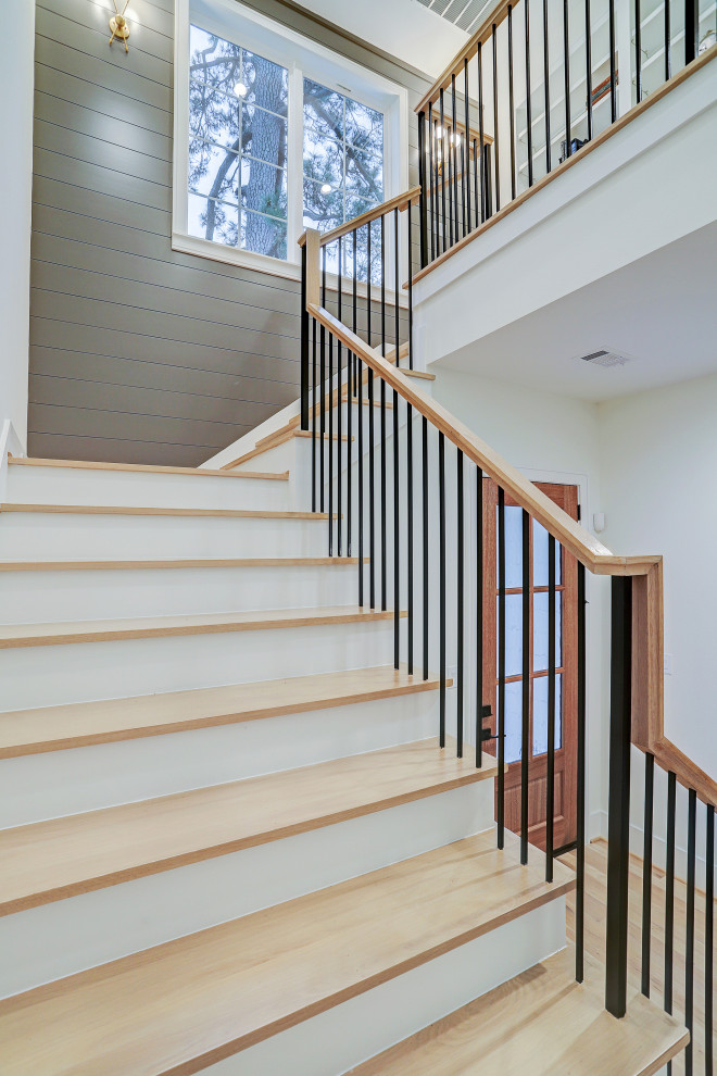 Diseño de escalera en U campestre grande con escalones de madera, contrahuellas de madera pintada, barandilla de madera y panelado